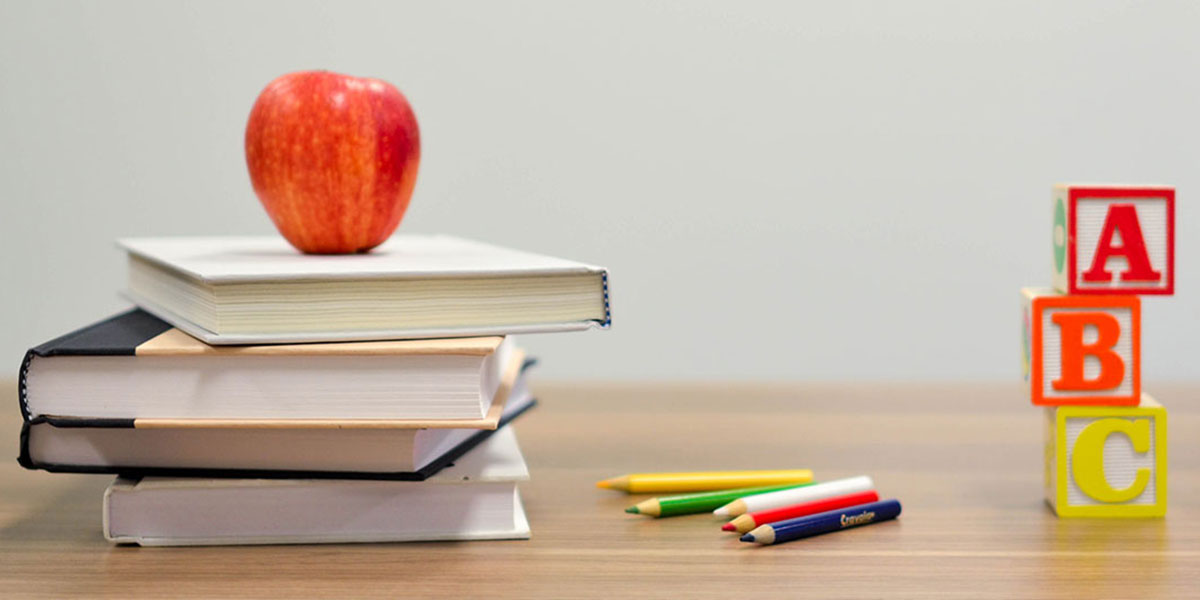 Desk with books, pencils, blocks and a apple on it